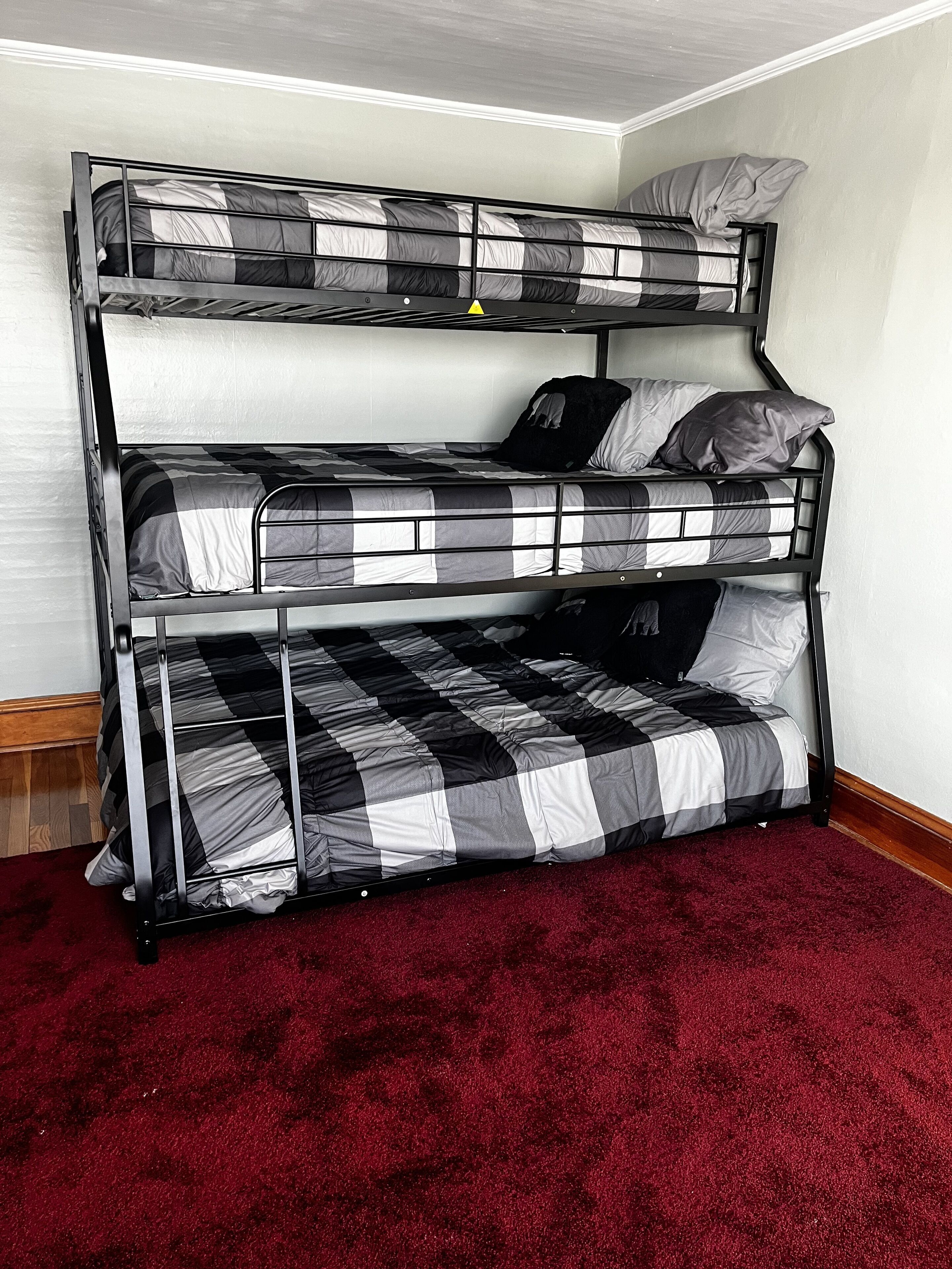 Una cama litera con una colcha a cuadros en una habitación con alfombra roja.