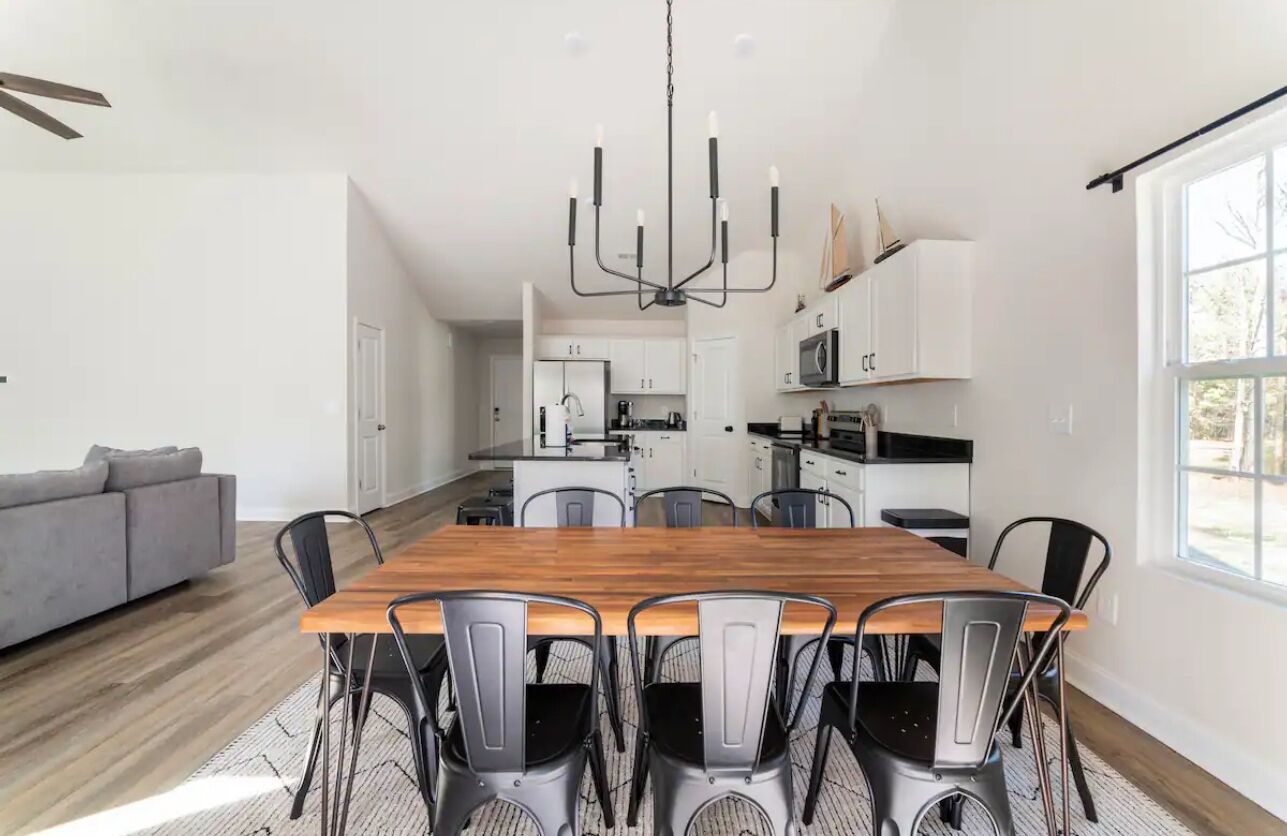 A modern kitchen with white cabinets, a wooden dining table, and black chairs.