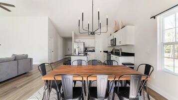 A modern kitchen with white cabinets, a wooden dining table, and black chairs.