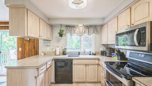 Una cocina moderna con armarios de madera, un microondas de acero inoxidable y un lavavajillas.
