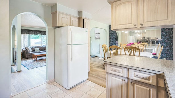 Una cocina moderna con armarios de madera, un refrigerador y un comedor con sillas y una mesa.