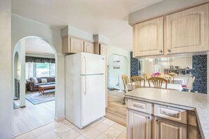 A modern kitchen with wooden cabinets, a refrigerator, and a dining area with chairs and a table. - Portland Charming, fully furnished, private, quiet and pets friendly Home.  (Portland)