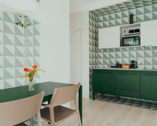 A modern kitchen with green cabinets, a white countertop, and a geometric backsplash.