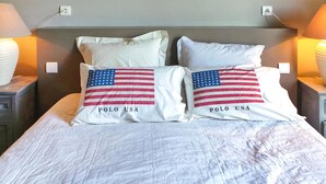 Cama com duas almofadas exibindo o desenho da bandeira americana e o texto "POLO USA".