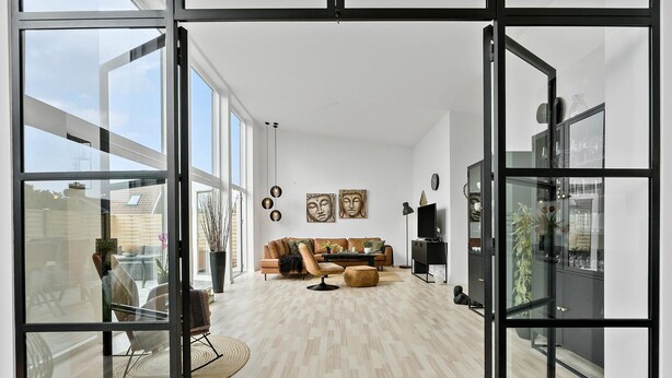 A spacious living room with a sofa set, a coffee table, and a TV. There are two Buddha head sculptures on the wall.