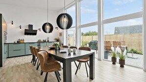 A modern kitchen with a dining area, large windows, and a view of the backyard.