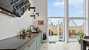 A modern kitchen with a large window, a dining area with outdoor seating, and a view of the backyard.