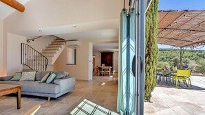 A modern interior with a staircase, a dining area, and a view of the outdoors. - Lovely home in Roussas (Roussas)