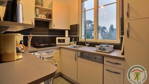 A modern kitchen with a microwave, stove, and sink. There is a window providing natural light and a view of the outside.