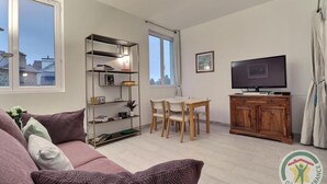 A living room with a sofa, a coffee table, a TV, a wooden cabinet, and a bookshelf.
