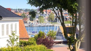 Een jachthaven met aangemeerde boten, omringd door woongebouwen en bomen.