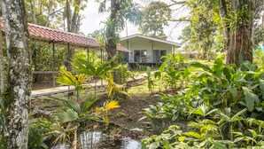 A house with a balcony, surrounded by lush greenery and a small pond. - Secluded Tropical Home in La Fortuna (La Fortuna)