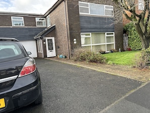 A two-story residential building with a garage, a driveway, and a well-maintained lawn. - Lowri Cottage Hotel (Birmingham)