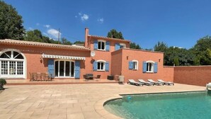 Une maison à deux étages dotée d’une piscine, d’un espace salon extérieur et d’un patio.