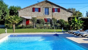 A stone house with a swimming pool and sun loungers.