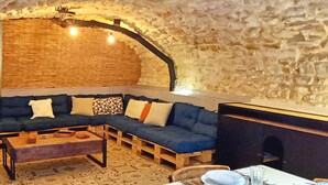 A cozy, stone-walled room with a sectional sofa, wooden coffee table, and a fireplace.
