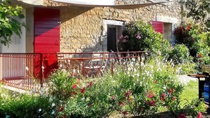 A stone building with red shutters and a balcony.