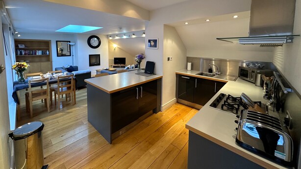 A modern kitchen with a central island, wooden flooring, and built-in appliances. - fantastic 2 bedroom with secure parking in Edinburgh's New Town (Edinburgh)