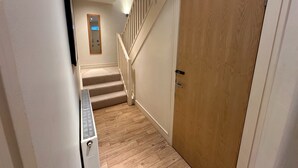 A narrow hallway with a wooden door, a vent, and a staircase with a wooden railing. - fantastic 2 bedroom with secure parking in Edinburgh's New Town (Edinburgh)