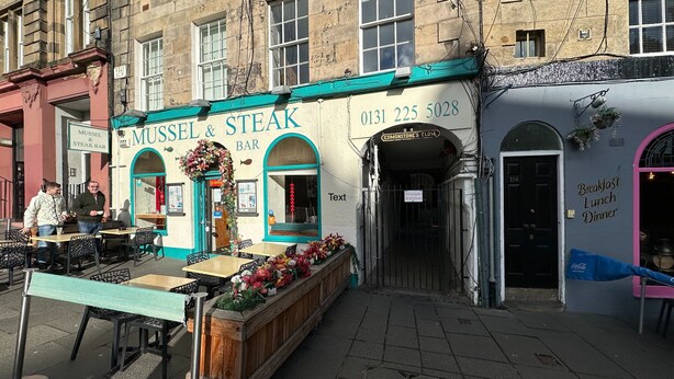 Een restaurant genaamd 'Mussel & Steak Bar' met terras en een houten buffettafel.