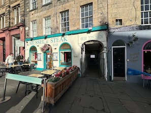 Un restaurante llamado 'Mussel & Steak Bar' con terraza y una mesa buffet de madera.