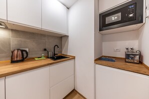 A compact kitchen with a microwave, kettle, and toaster on the countertop.