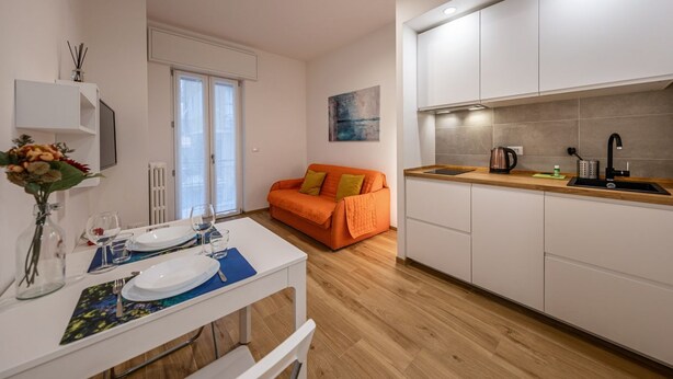A modern kitchen with white cabinets, a wooden countertop, and a dining area with a table set for two. - 🏠 PROPERTY DESCRIPTIONCasa Simona is a modern and renovated apartment, located in a quiet area just a few minutes' walk from the center of Rapallo. With shops, restaurants, and public transport nearby, it’s the ideal starting point to explore the Gu (Rapallo)