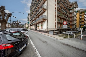 Ein mehrstöckiges Wohngebäude mit Balkonen, einem Verbotsschild und geparkten Autos an der Straße.