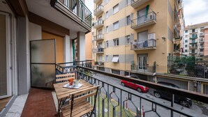 A balcony with a table and chairs, a view of a street with cars, and a building with balconies and windows. - 🏠 PROPERTY DESCRIPTIONCasa Simona is a modern and renovated apartment, located in a quiet area just a few minutes' walk from the center of Rapallo. With shops, restaurants, and public transport nearby, it’s the ideal starting point to explore the Gu (Rapallo)