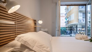 A hotel room with a wooden headboard, a bed with white linens, a bedside table, and a view of the outside balcony. - 🏠 PROPERTY DESCRIPTIONCasa Simona is a modern and renovated apartment, located in a quiet area just a few minutes' walk from the center of Rapallo. With shops, restaurants, and public transport nearby, it’s the ideal starting point to explore the Gu (Rapallo)