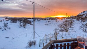 A snowy landscape with a sunset, a wooden fence, and a utility pole.