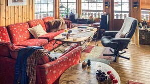 A cozy living room with a red patterned sofa, a wooden coffee table, and a black office chair.
