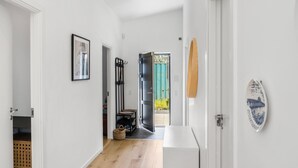 Un pasillo con paredes blancas, suelo de madera, una puerta que da a un balcón y un cuadro enmarcado en la pared.