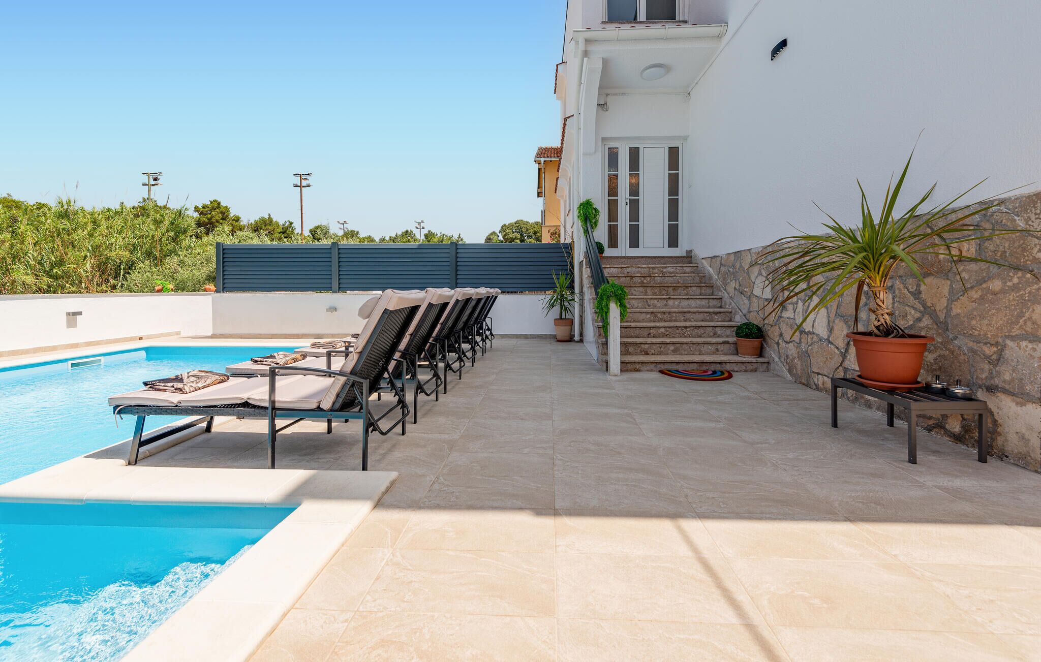 A pool area with lounge chairs and a staircase leading to a building.