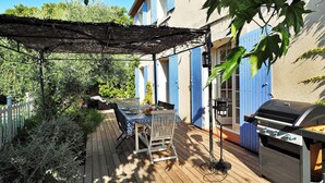 A wooden deck with a table and chairs, a barbecue grill, and a pergola. - Les Lauriers De Fontvieille (Fonvieille)