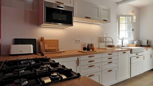 A modern kitchen with white cabinetry, a built-in microwave, a gas stove, and a window providing natural light. - Les Lauriers De Fontvieille (Fonvieille)