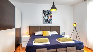 Un dormitorio moderno con una cama grande, un cuadro de cebra, una lámpara de noche y una lámpara de pie.
