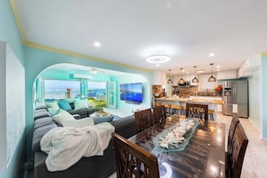 A modern living room with a sofa, dining table, and kitchen area with a view.