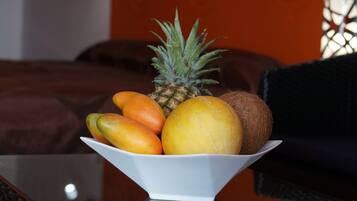 Un tazón de fruta sobre una mesa, con una cama al fondo.