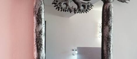 Un espejo con un marco similar a un árbol en una habitación con una cama y una mesita.