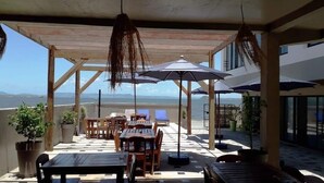 A covered outdoor seating area with tables and chairs, umbrellas, and potted plants. - Hotel de la Poste (Antsiranana)