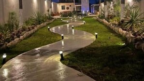 A modern building with a curved pathway and palm trees. - Mizu Villa (Chelem)