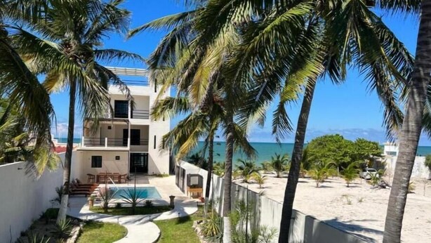 A modern multi-story building with a pool, surrounded by palm trees and a sandy beach. - Mizu Villa (Chelem)