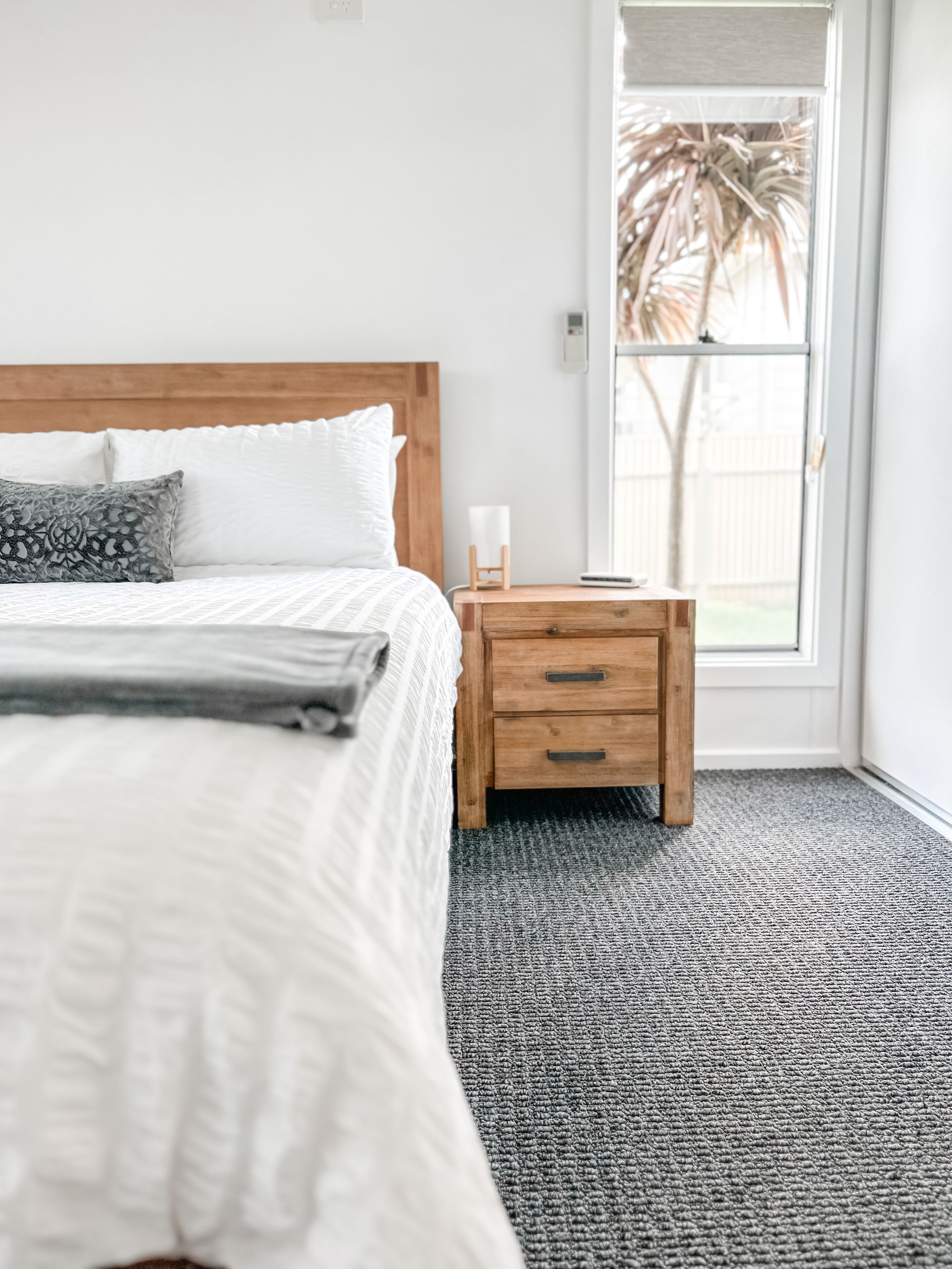 A bedroom with a bed, a nightstand, and a window.