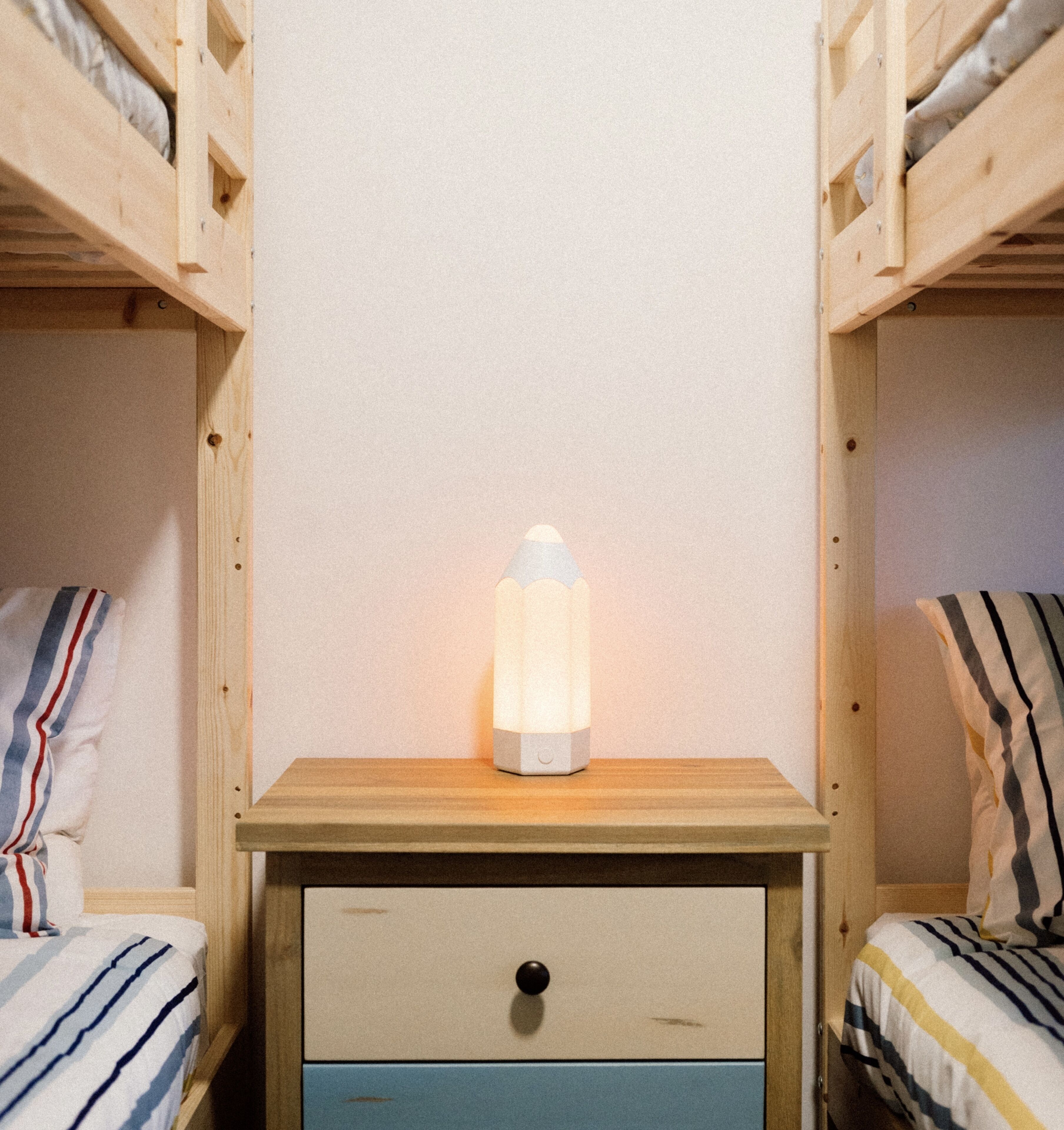 A bunk bed room with a bedside table, a lamp, and a drawer.