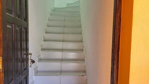 Un escalier aux marches blanches menant à une porte dotée d’une poignée en laiton.