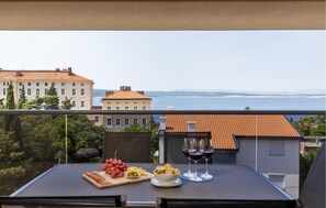Enjoy a meal on the balcony with a view of the water and distant buildings.