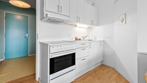 Une cuisine compacte avec des meubles blancs, un four encastré et un évier.