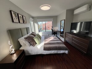 Relax in a spacious room with a large bed, flat-screen TV, and desk area.