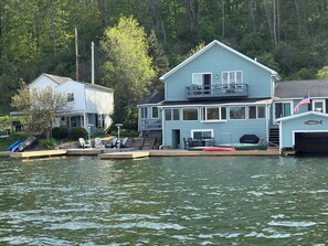 A waterfront property with a dock, a covered area with seating, and a garage with an American flag.